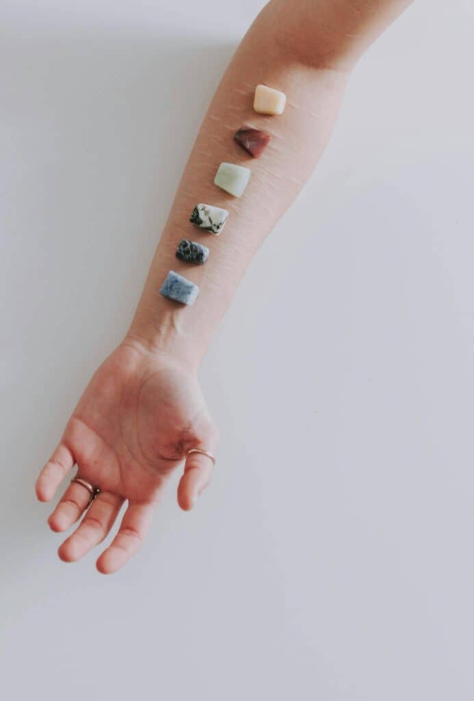 A human arm with chakra stones for spiritual healing and energy balance therapy.